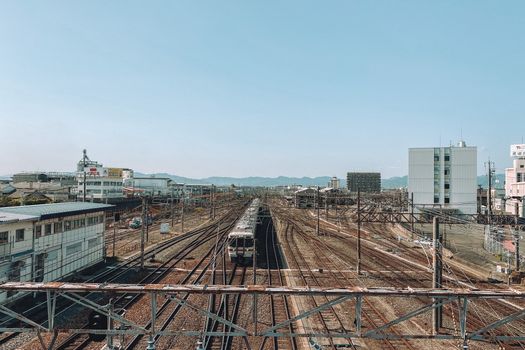 Scenic aerial view of train tracks leading through Toyohashi, Japan, under a clear sky.