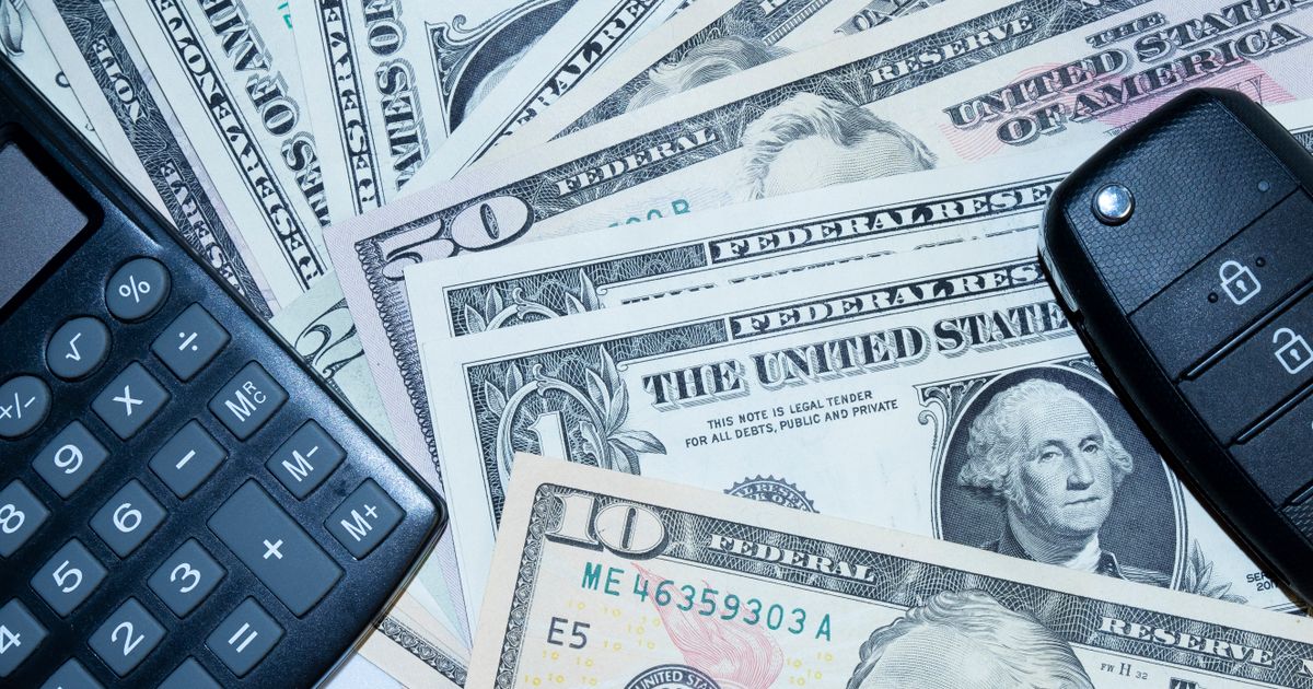 US dollars, calculator, and car keys representing finance and investment tools.