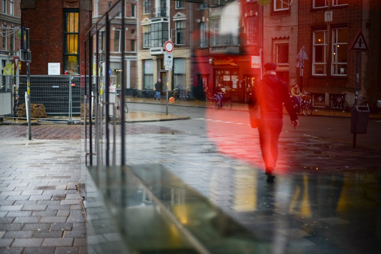 Man Walking On Road Reflected On Glass Window