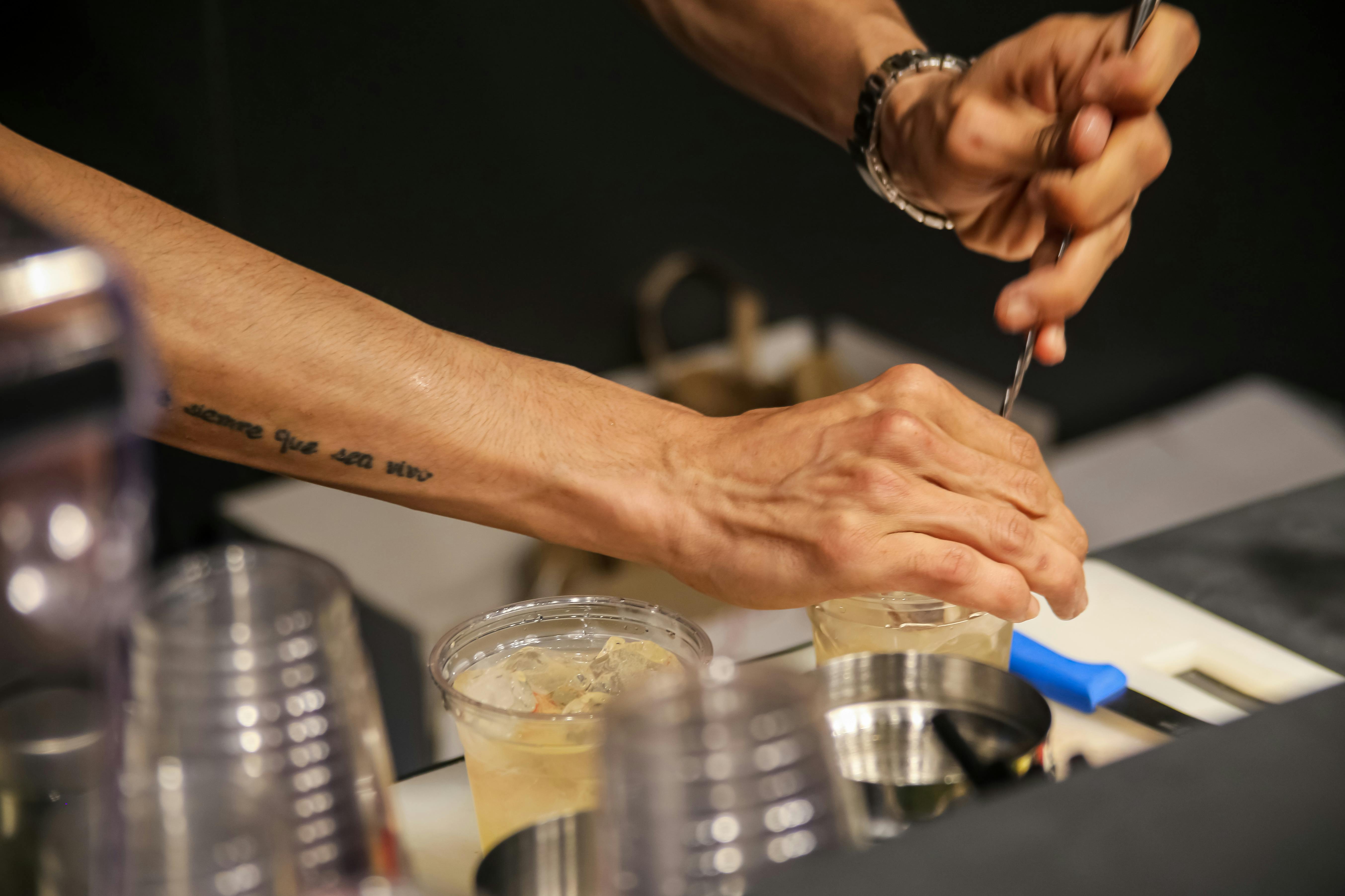 Bartender ida iha bar, uja limonada, nimbu achar, no espesiaria sira, ho sorrisu, iha iluminasaun ne'ebé aat, hanesan simbolu