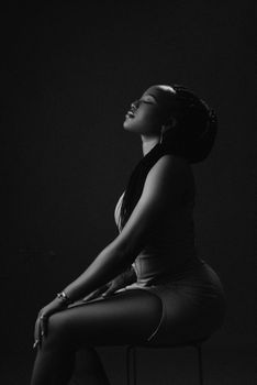 Artistic black and white portrait capturing a woman with eyes closed, sitting and posing elegantly.