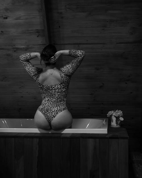 Black and White Shot of a Woman in Leopard Pattern Swimsuit Sitting on a Bath Tub