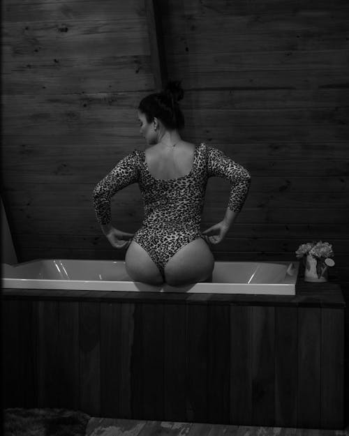 Black and White Photo of a Woman Sitting on a Bath Tube