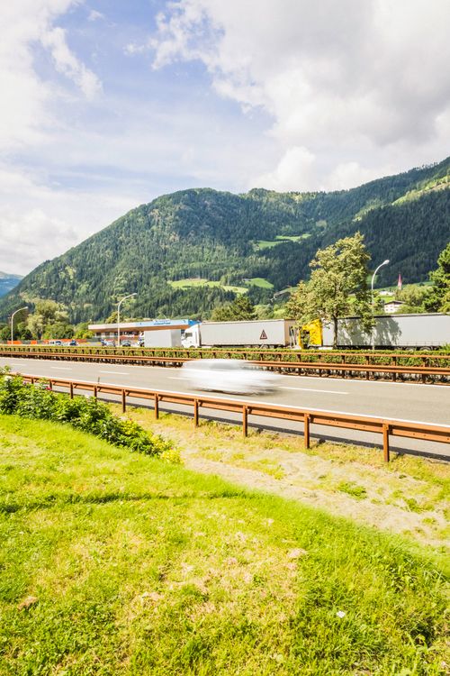 Free Idyllic countryside highway amidst mountains with cars in motion blur, perfect for travel themes. Stock Photo