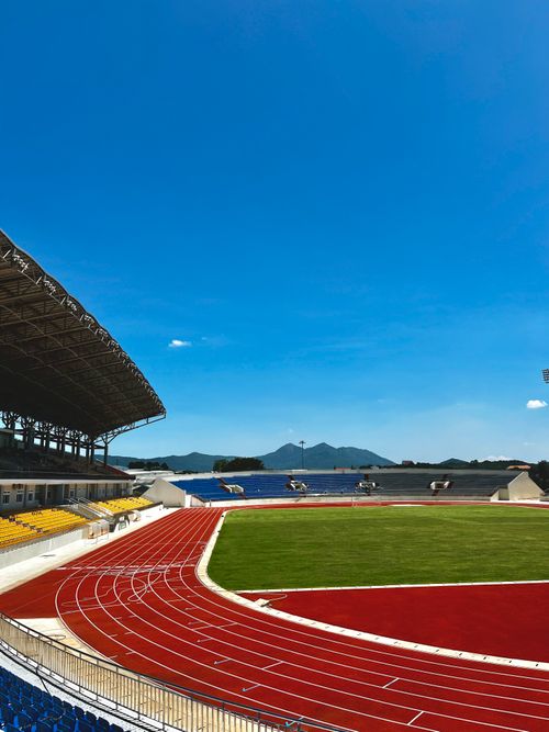 Free Spacious outdoor stadium with vibrant running tracks and green soccer field under blue sky. Stock Photo