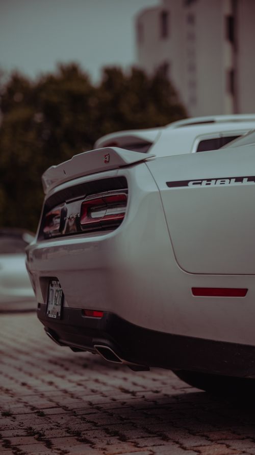 Free Close-up of the rear of a white Dodge Challenger in a parking lot with a dramatic angle. Stock Photo