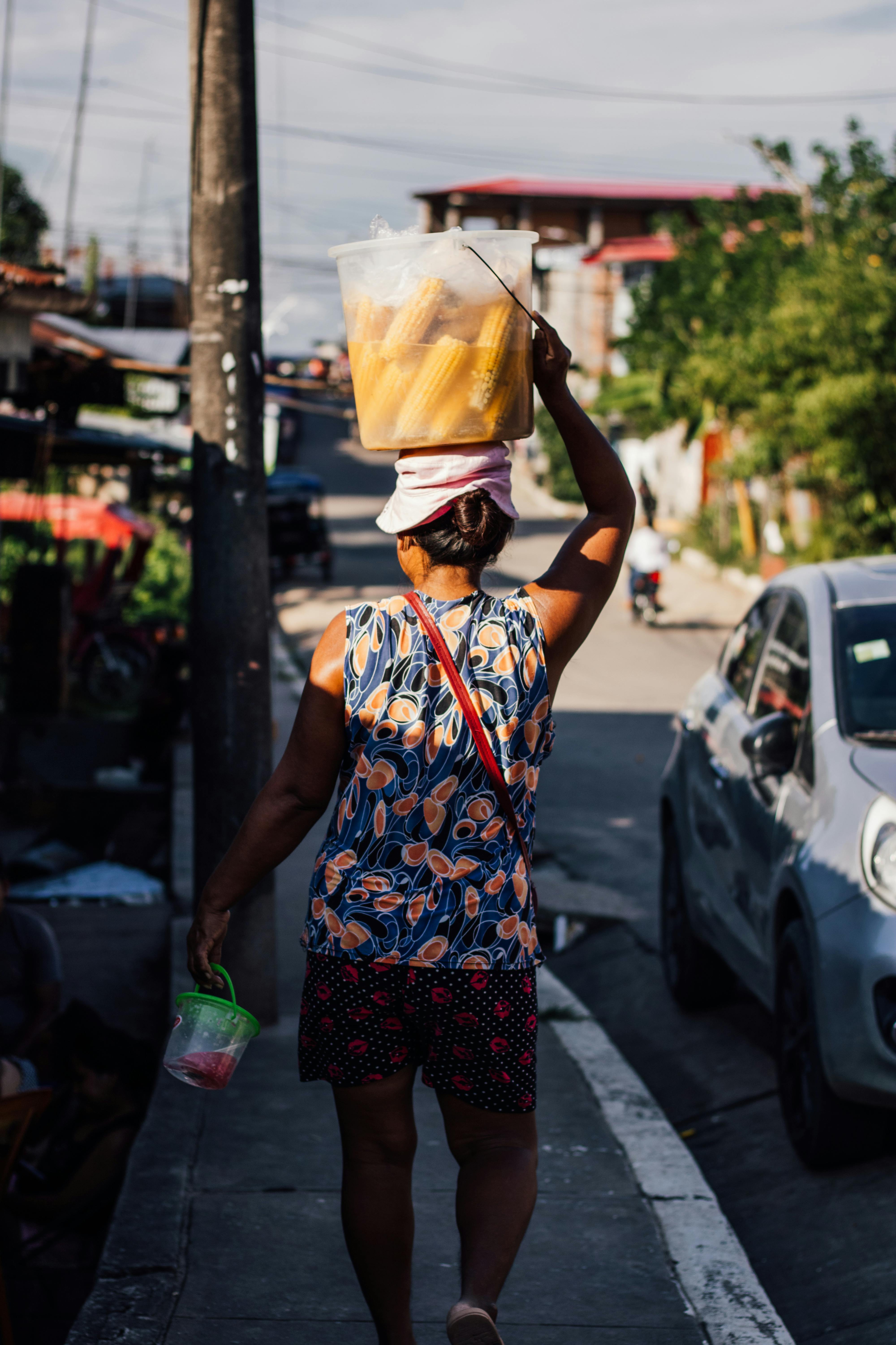 A woman walks on a Yurimaguas street carrying a basket on her head.