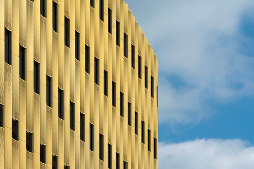 Free Yellow building facade with a modern design against a clear blue sky, emphasizing urban architecture. Stock Photo