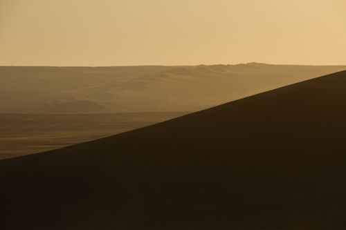 Free Capture the tranquility of a barren desert landscape with rolling hills at sunset. Stock Photo