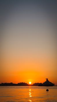 Tranquil sunset view over the ocean with a yacht silhouette, perfect for relaxing and meditation themes.