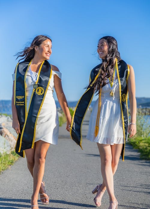 Women Wearing Graduation Sashes Holding Hands