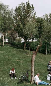 A serene park scene with people enjoying leisure time under sunlit trees, highlighting relaxation and nature.