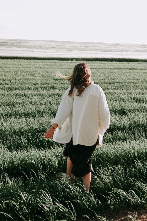 Free A woman walks through a lush green field, enjoying a sunny day outdoors. Stock Photo