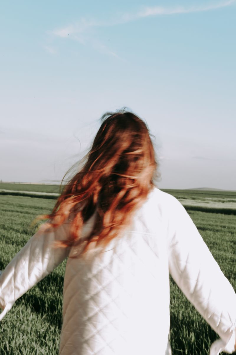 Woman with long copper-red hair in a white shirt outdoors