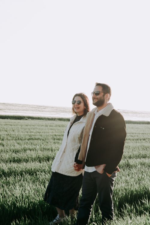 Free Happy couple walking hand in hand in a sunlit meadow, enjoying a peaceful moment together. Stock Photo