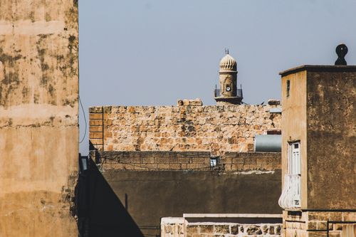 Free A sunlit urban scene featuring historic architecture and stone walls. Stock Photo