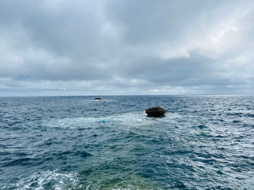 Free Peaceful ocean scene with a solitary boulder under a cloudy sky, capturing the serene beauty of the sea. Stock Photo