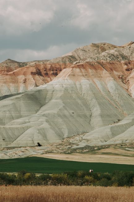 Beautiful layered mountains with vibrant fields in the foreground, showcasing natural textures and tones.
