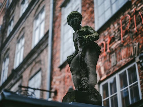 Bronze Figure Against Brick Building
