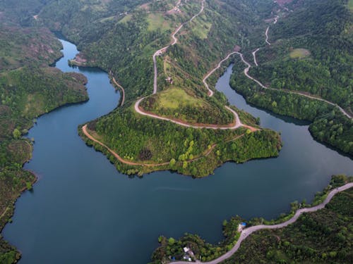 Aerial View of a River in the Valley Surrounded by Hills Covered with Green Trees