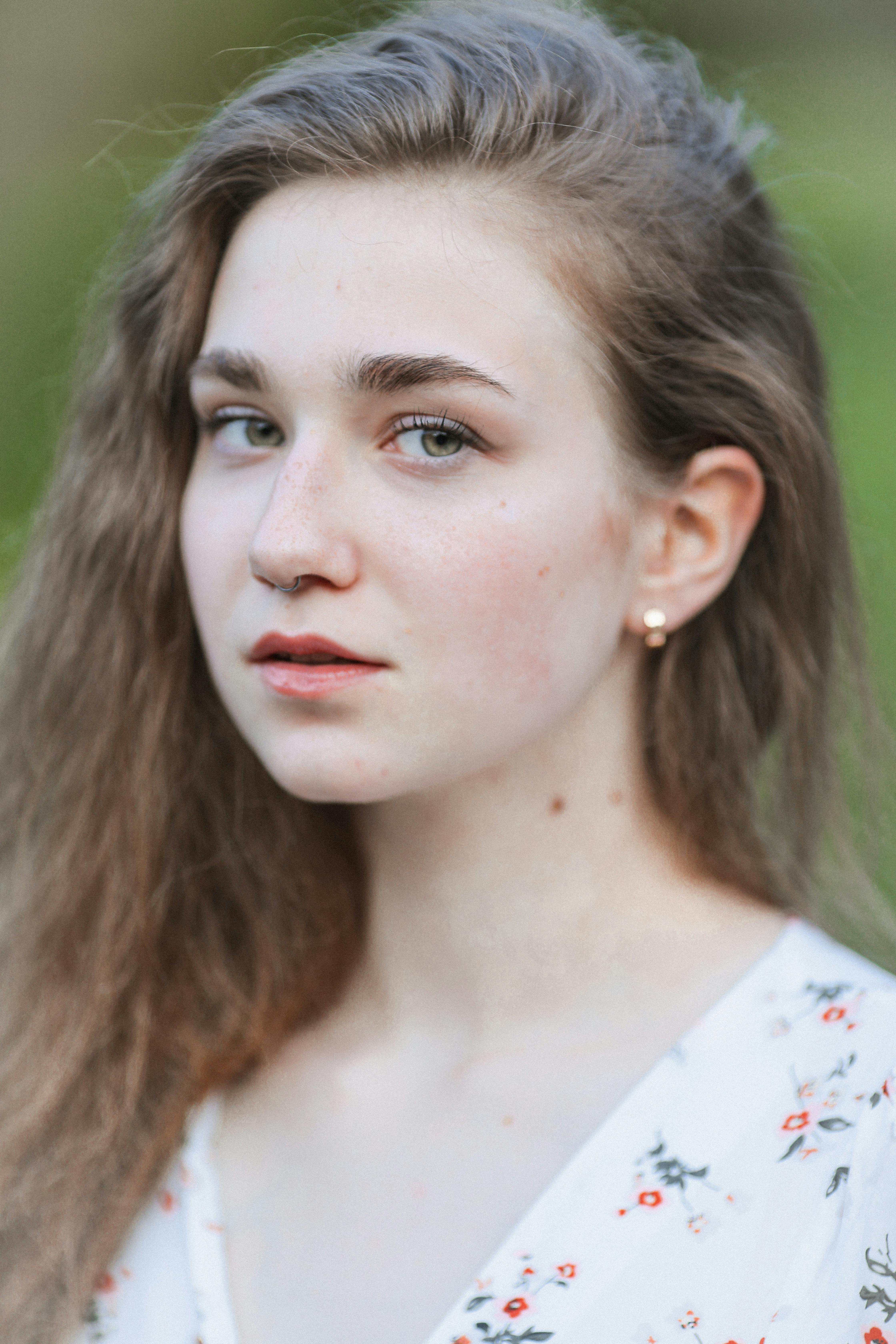 Portrait of a young woman with natural beauty, posing outdoors in a floral dress.