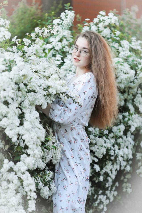 Beautiful Woman in Floral Dress Posing Near White Flowers