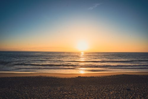 Free A captivating view of the sunset over calm ocean waves, offering a peaceful beachscape. Stock Photo