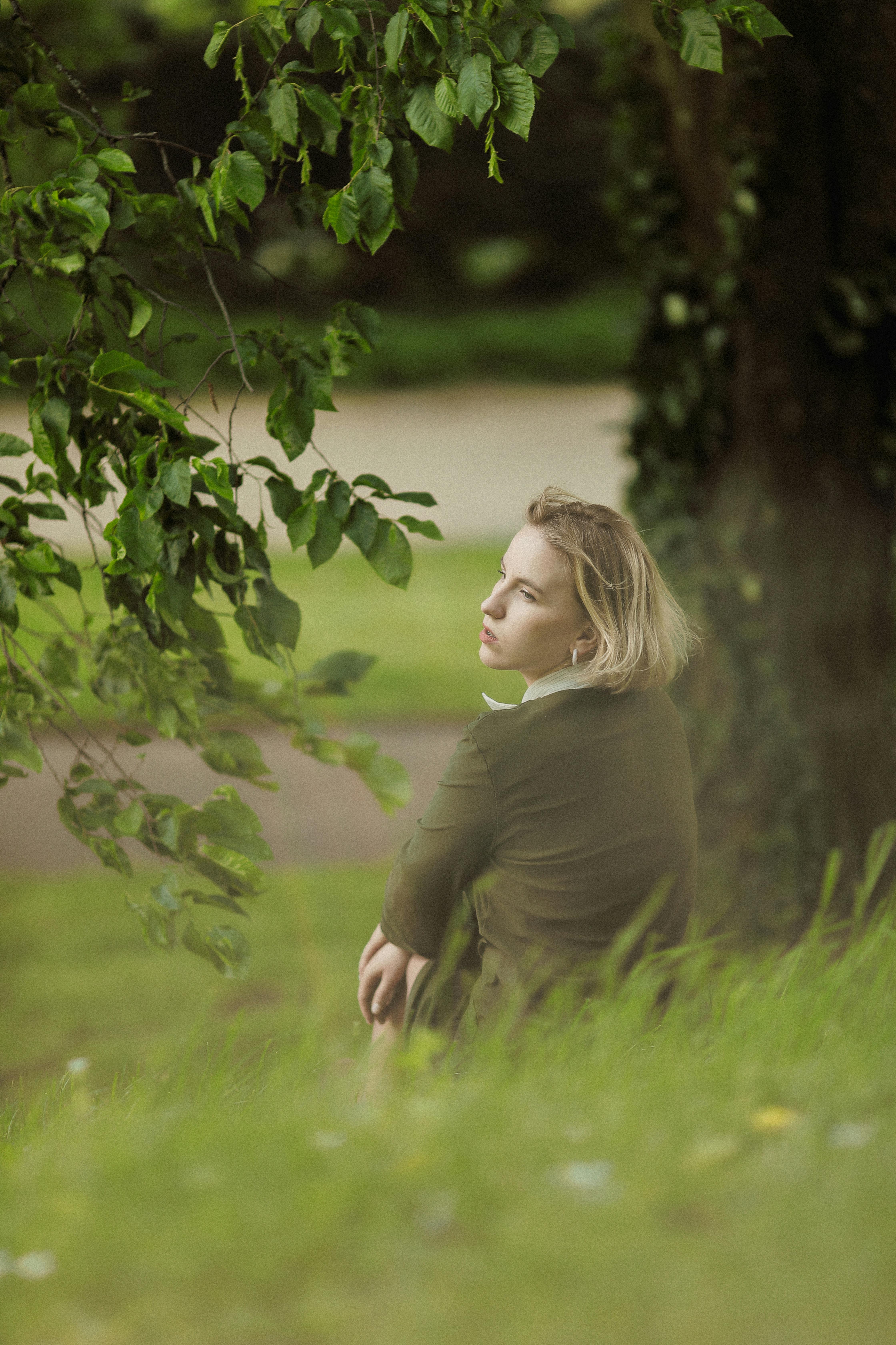 young woman sitting on a grass field in summer