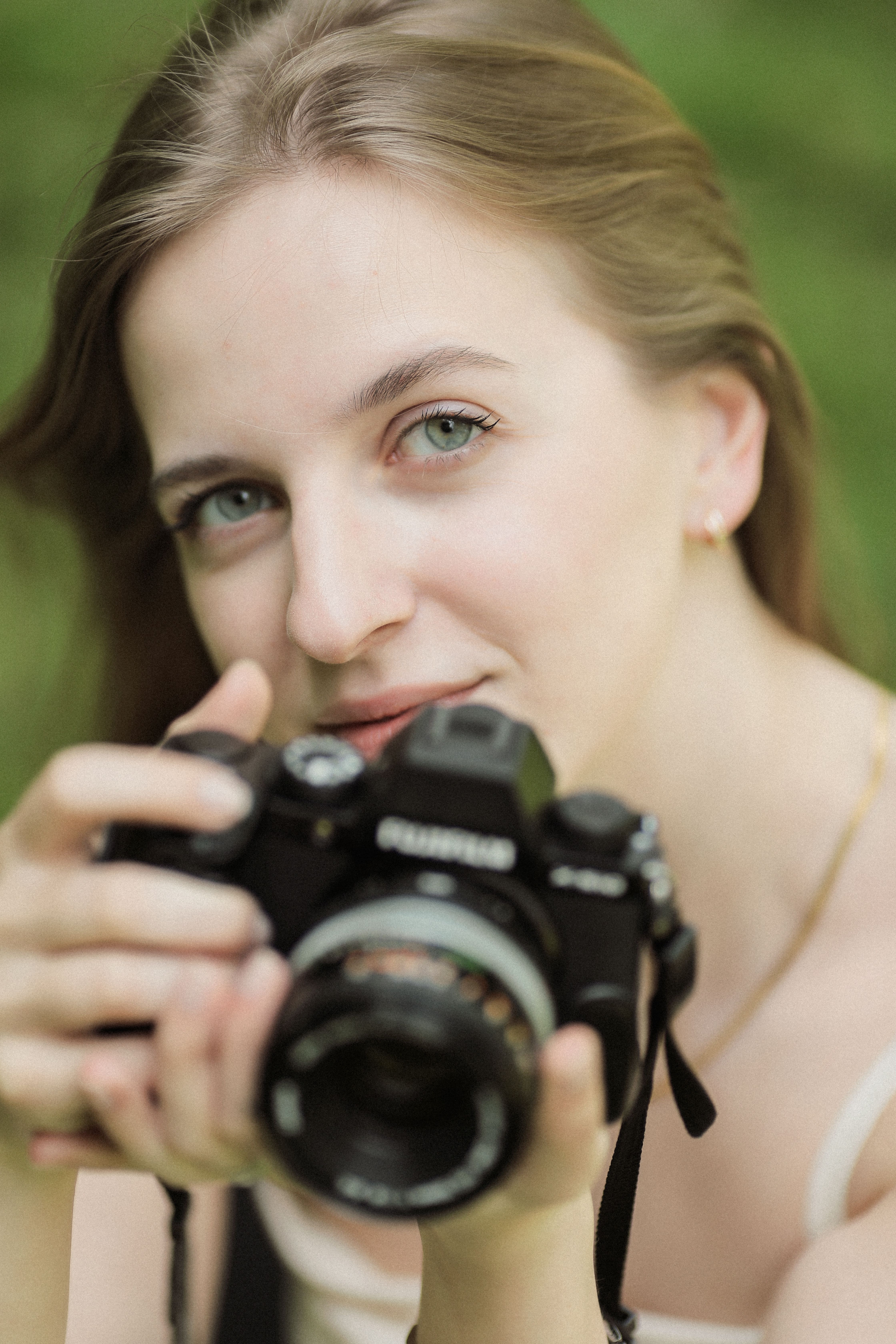 A young woman with a camera capturing moments in a natural setting.