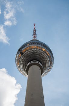 The iconic Berlin TV Tower captured from below, set against a clear blue sky.