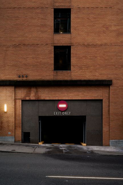 Brick building with 'Exit Only' sign above the garage in an urban setting.