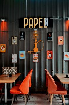 A stylish café in Istanbul with retro wall signs, orange chairs, and tables.