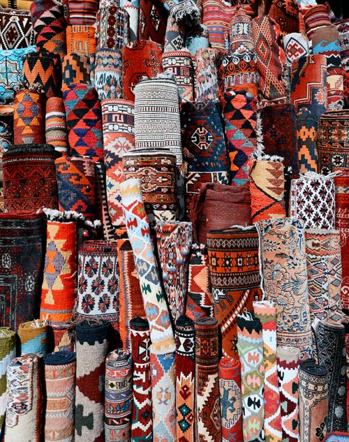 Free A colorful array of traditional rugs with intricate patterns at a market stall. Stock Photo
