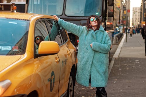 Young Woman in a Blue Coat Standing next to a Car on the City Street