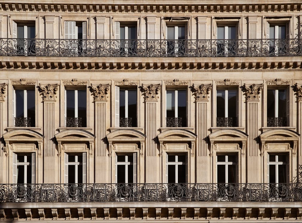 Free Elegant facade of a Parisian building showcasing detailed ornamentation and wrought iron balconies. Stock Photo