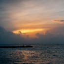 宁静的日落下，海面上云层壮观，码头轮廓分明，共同营造出一片平静的海景