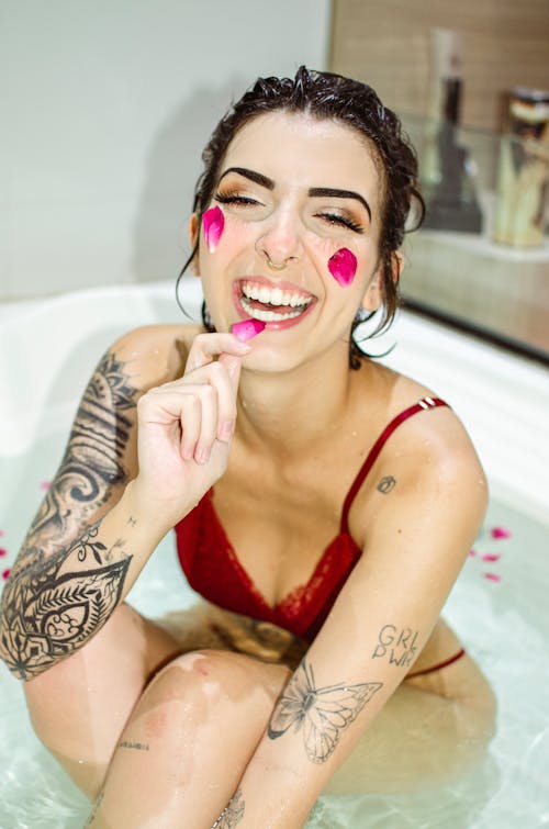 Woman with Rose Petals on her Face Sitting in a Bathtub 