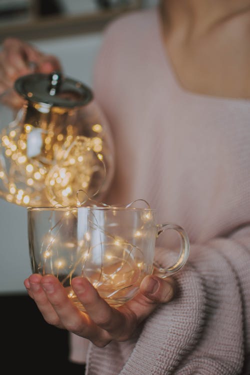 Personne Tenant Une Tasse En Verre Transparent Remplie De Mini Guirlandes Lumineuses