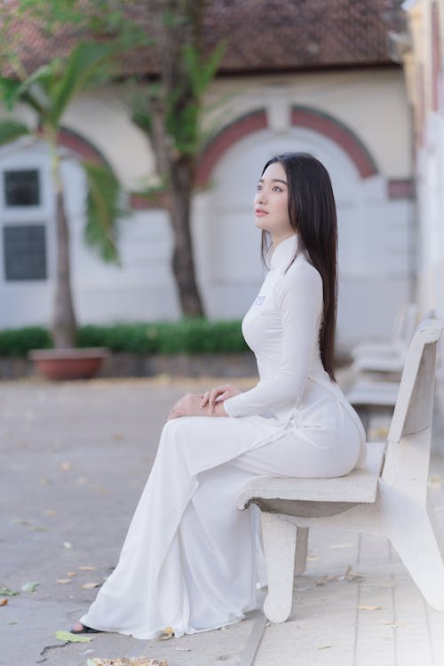 Young Woman in a White Dress Sitting on a Bench 