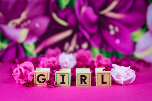 木制块拼写着“女孩”，周围装饰着粉红色的花卉和玫瑰