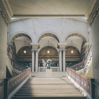 Elegant museum interior with grand staircase, arches, and classic sculptures.（イメージ）