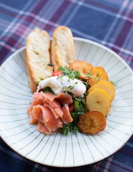 Delicious smoked salmon breakfast with poached egg, accompaniments on elegant plate.