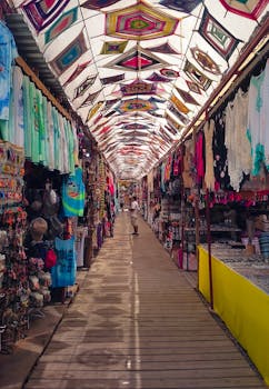 Explore a traditional Mexican market alley filled with colorful textiles, crafts, and a vibrant canopy overhead.