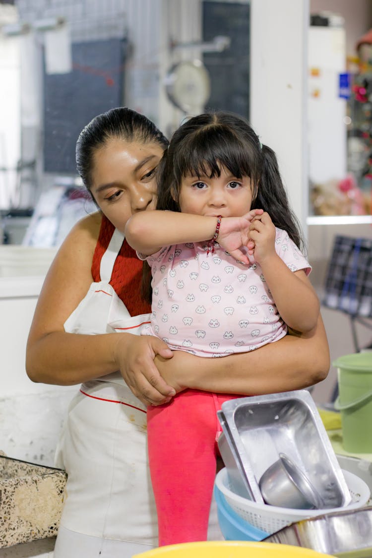 Woman Holding Girl In Kitchen