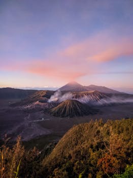Scenic view of Mount Bromo at sunrise with colorful clouds and volcanic smoke in Pasuruan, Indonesia.
