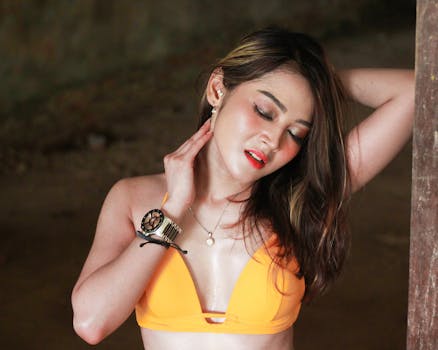 Beautiful woman in a striking orange bikini posing with an artistic, sensual expression.