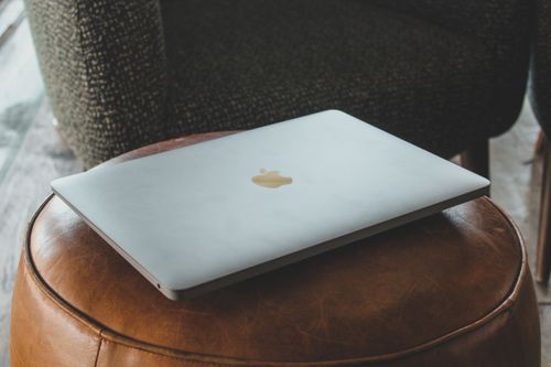 Free A modern laptop rests on a stylish leather ottoman in a cozy indoor environment, highlighting technology and lifestyle. Stock Photo