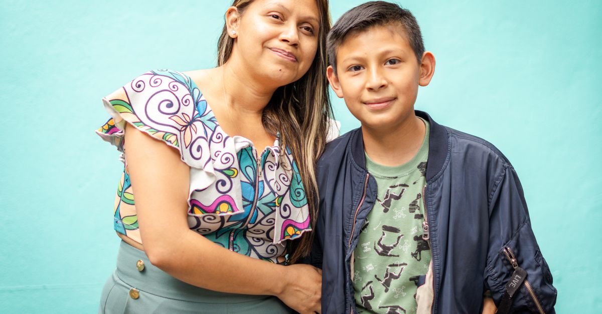 Una madre sonriendo mientras abraza a su hijo, con documentos fiscales de fondo.