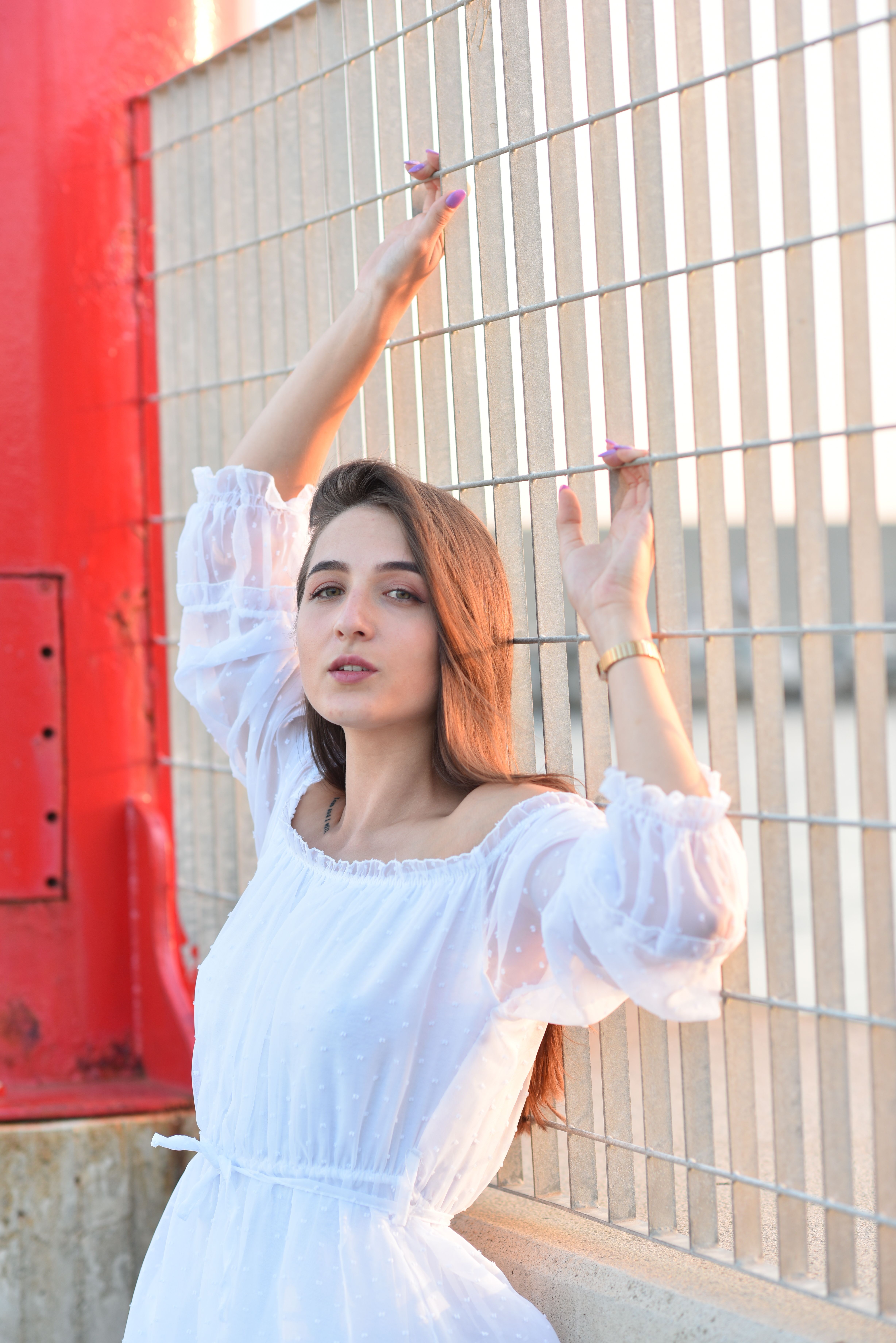 Young Woman in a White Dress Standing against a Fence · Free Stock Photo