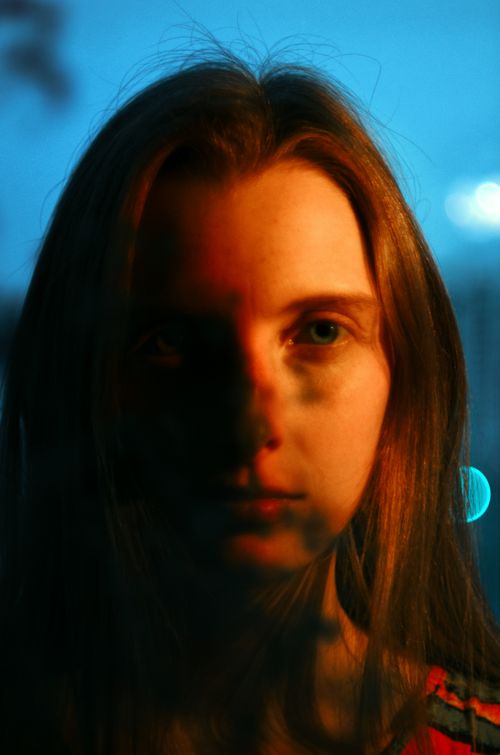 Free Close-up portrait of a woman at dawn with dramatic and artistic lighting casting shadows. Stock Photo